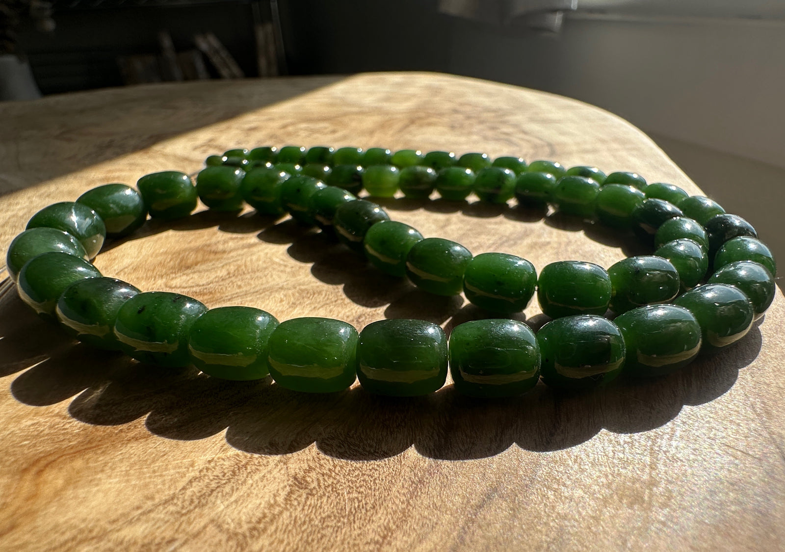 Dark Green Jade barrel shape beads on a wooden base