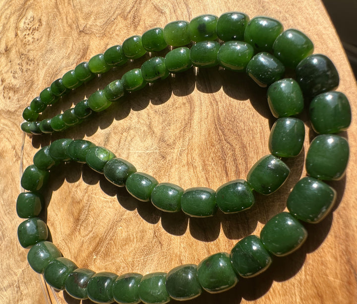 Dark Green Jade barrel shape beads on a wooden base