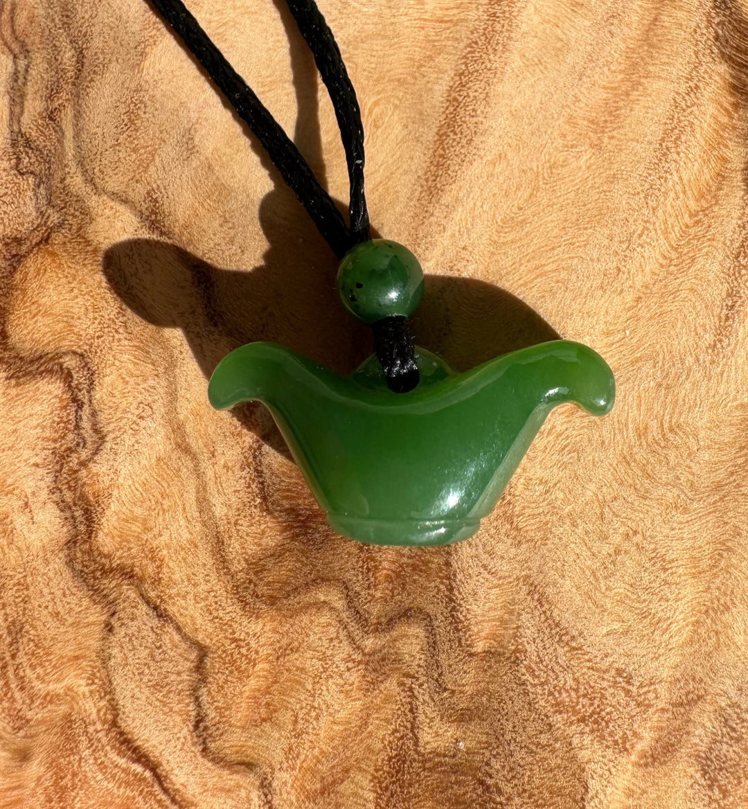 22mm bright green nephrite jade pendant on a black cord with a curved wave shape