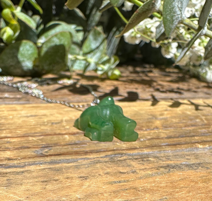 Canadian nephrite jade deer pendant on a silver chain resting on a weathered wooden surface