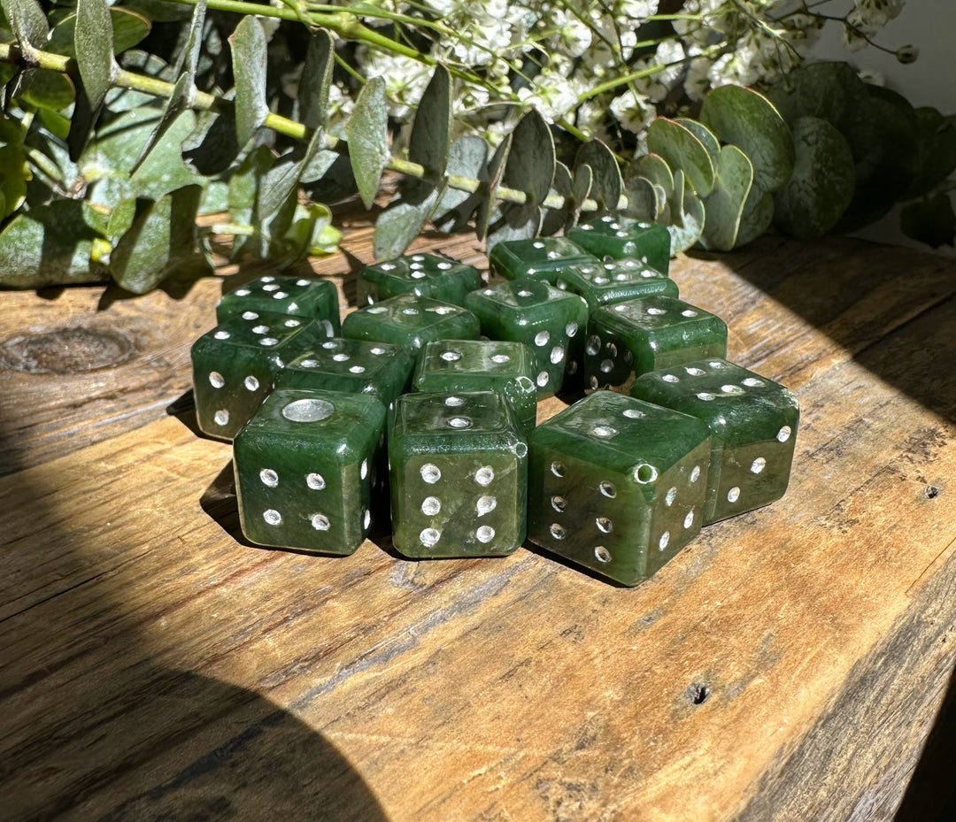 Vintage green jade dice with white pips scattered on a rustic wooden surface.