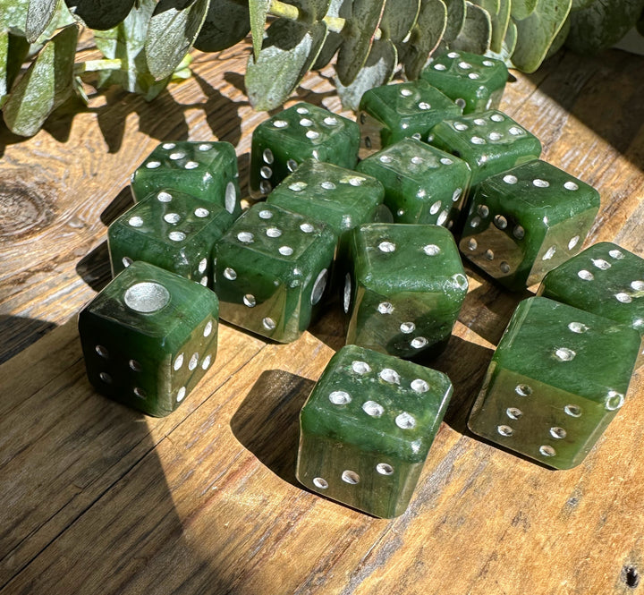 Vintage green jade dice with white pips on a weathered wood surface