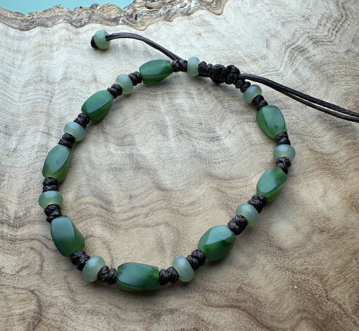 Green gemstone bracelet with oval and round beads on black braided cord and sliding knot.
