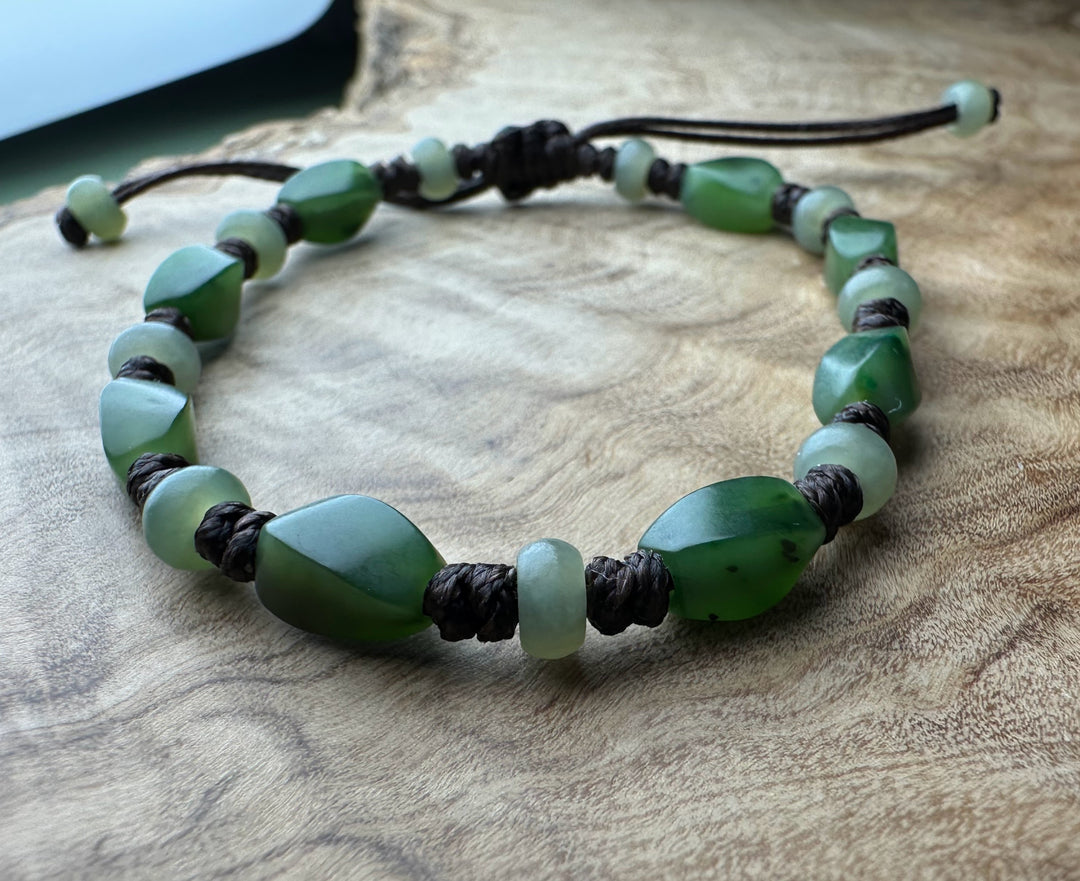 Bracelet of green jade beads with irregular chunky stones and pale round beads on a dark braided cord