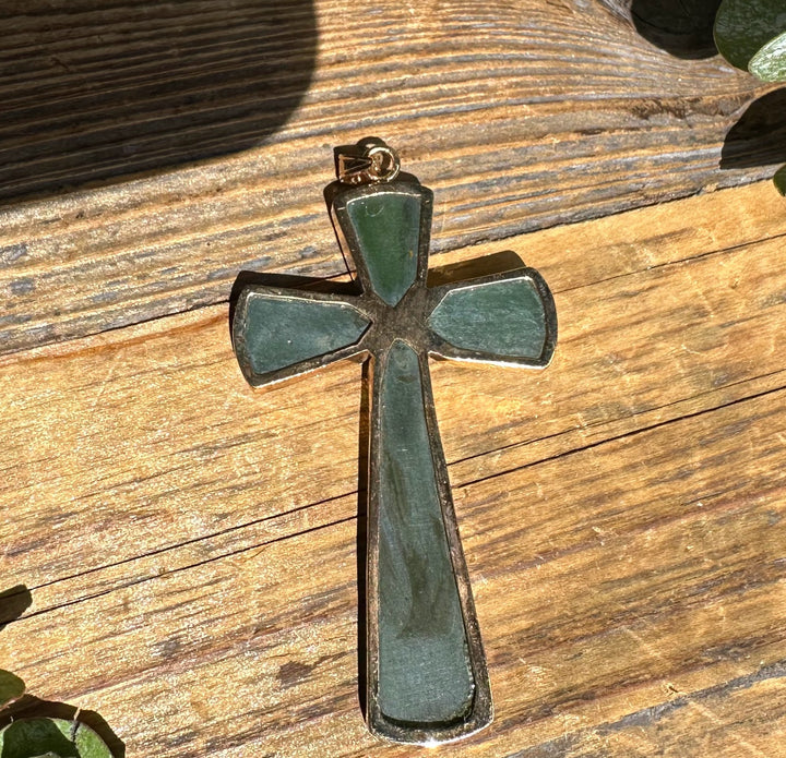 Vintage large jade cross pendant on a weathered wooden surface