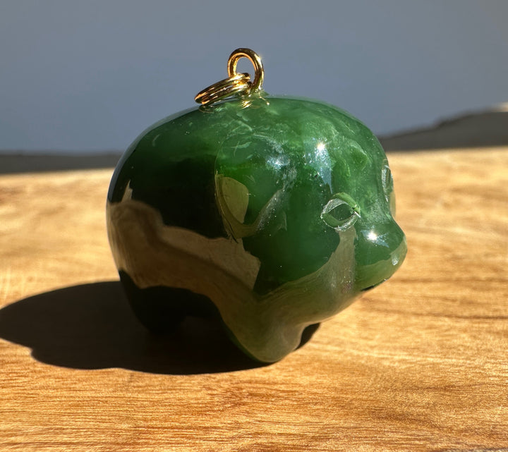 Green jade pig with gold jump ring on a wooden surface