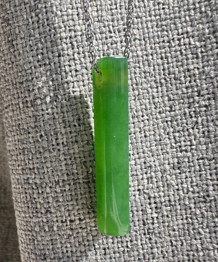 Bright Green Siberian Jade Pendant against a grey fabric