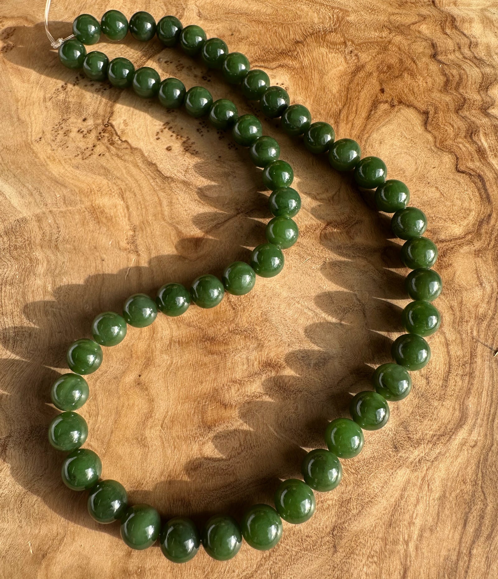 8mm dark green Canadian unstrung beads arranged on a wooden surface