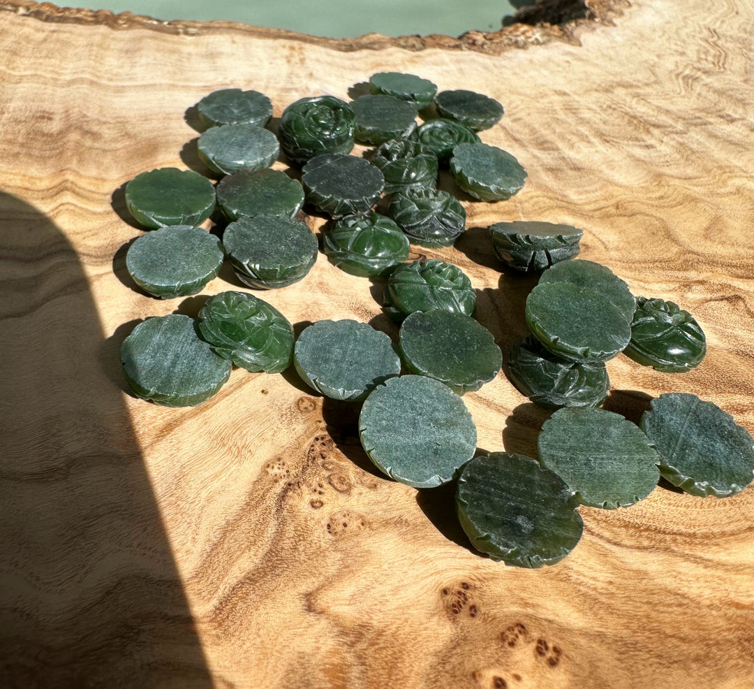 Cluster of flat round dark green jade cabochons with scalloped edges on a wooden board