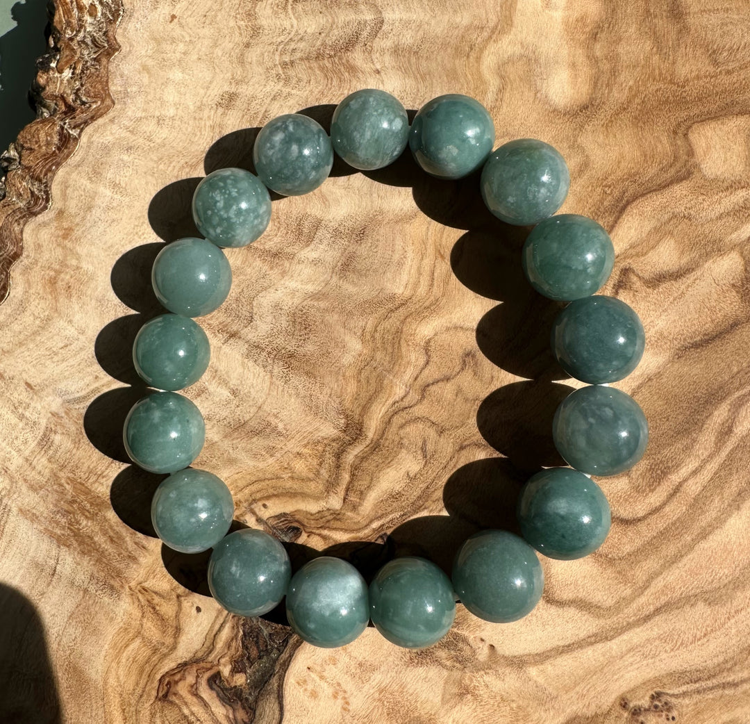 Top-down view of Guatemalan jadeite bead bracelet 12mm on wood showing round beads