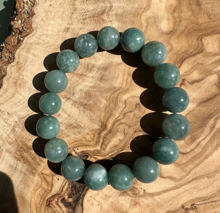 Top-down view of Guatemalan jadeite bead bracelet 12mm on wood showing round beads