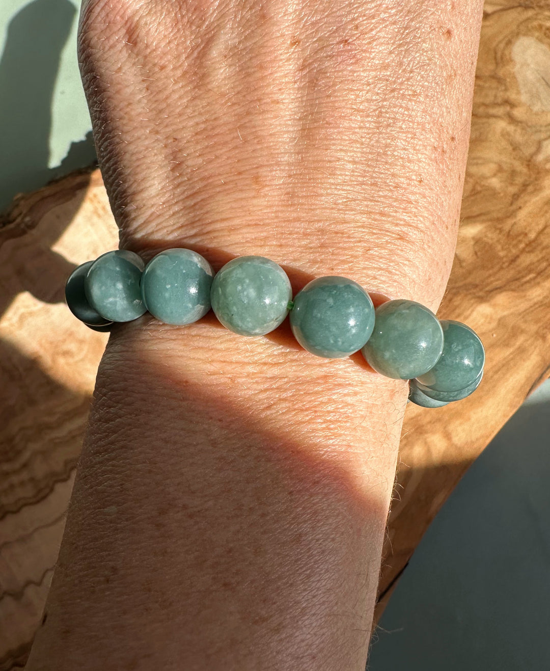 Guatemalan jadeite bead bracelet 12mm worn on the wrist with round glossy beads visible