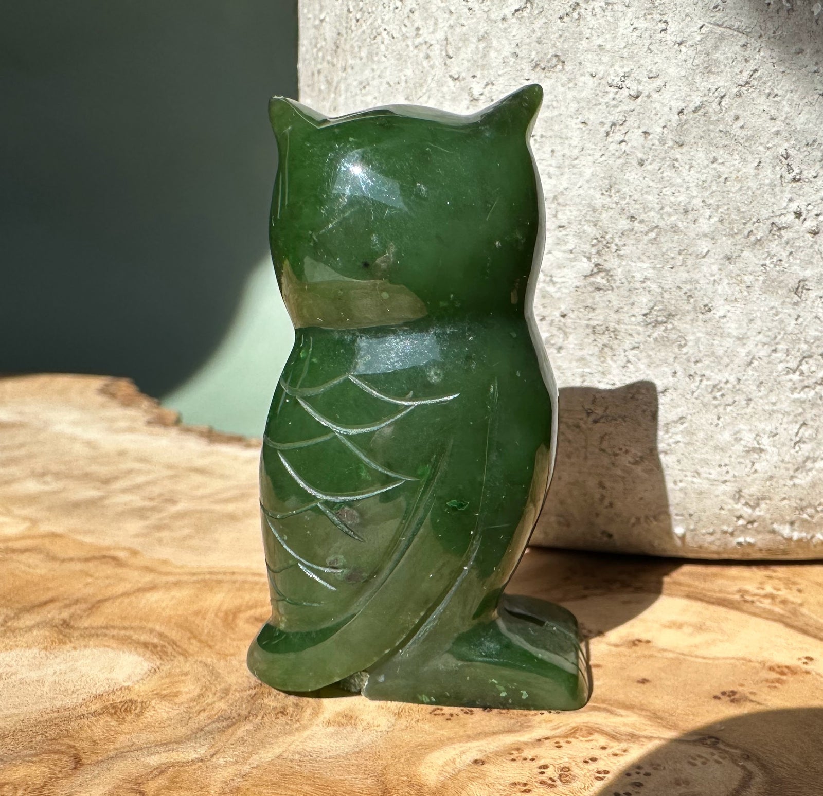 Back view of the two inch dark green jade owl figurine with carved feather details.