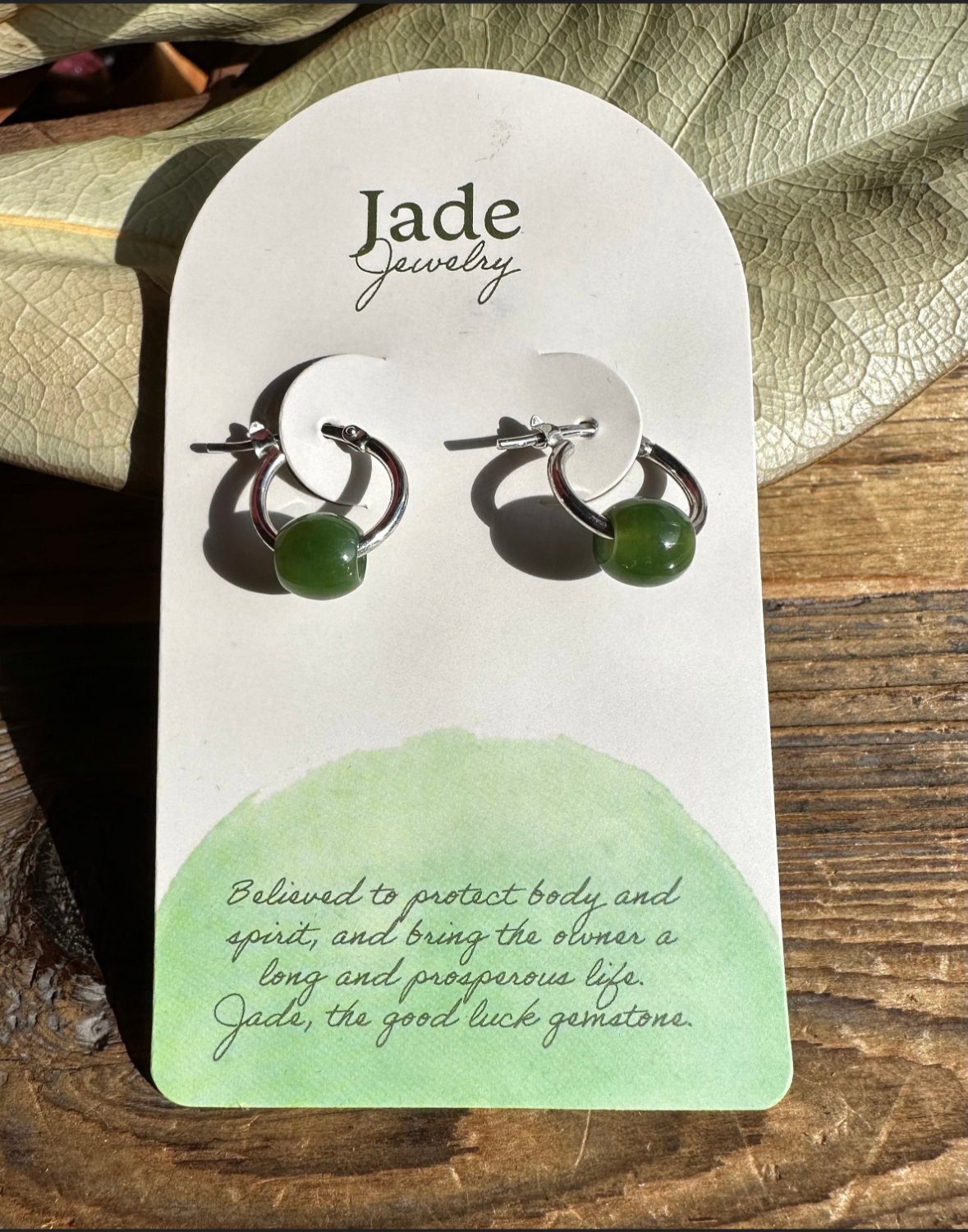 Green jade bead on a sterling silver hoop earring displayed on a Jade Jewelry card