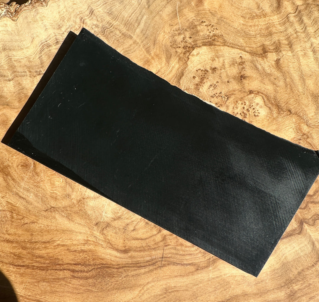 A black rectangular jade on natural wood surface.