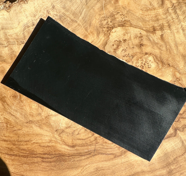 A black rectangular jade on natural wood surface.