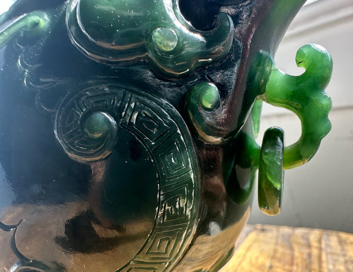 Dark green jade Phoenix teapot side with swirling scrolls, a geometric border, and a curved handle.