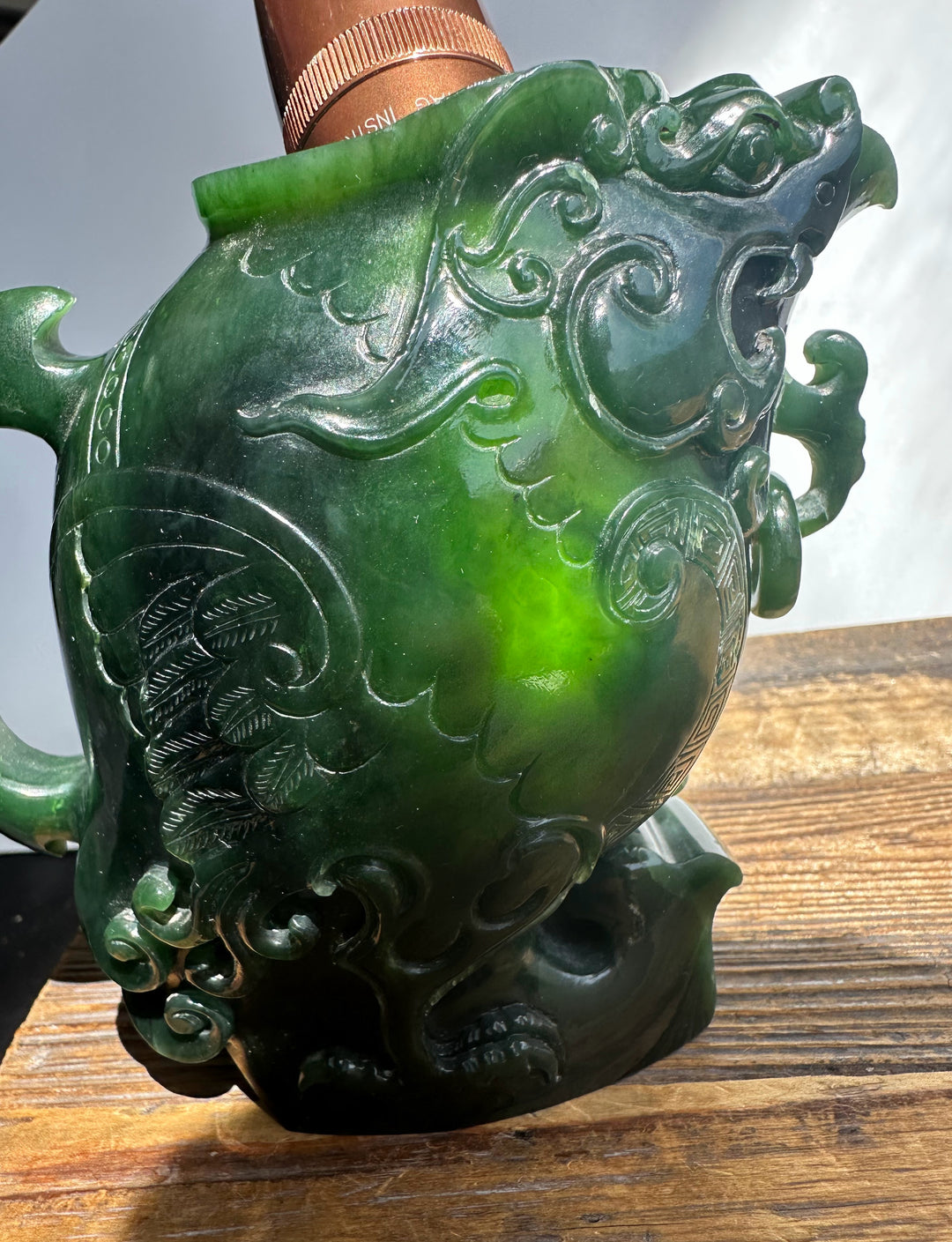 Dark green jade Phoenix teapot showing leaf engravings and swirling patterns on its glossy body.