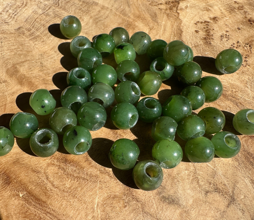 8mm Canadian jade beads with large holes arranged in a loose strand on a wooden table