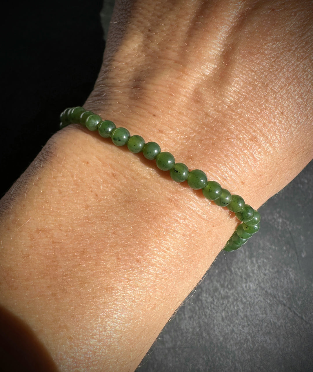 A green beaded bracelet worn on a person&