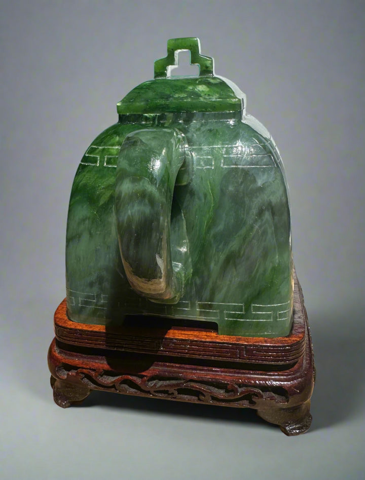 Angled side view of Polar Jade Teapot seven inches, spout to the right and jade handle in front on a carved wooden base.