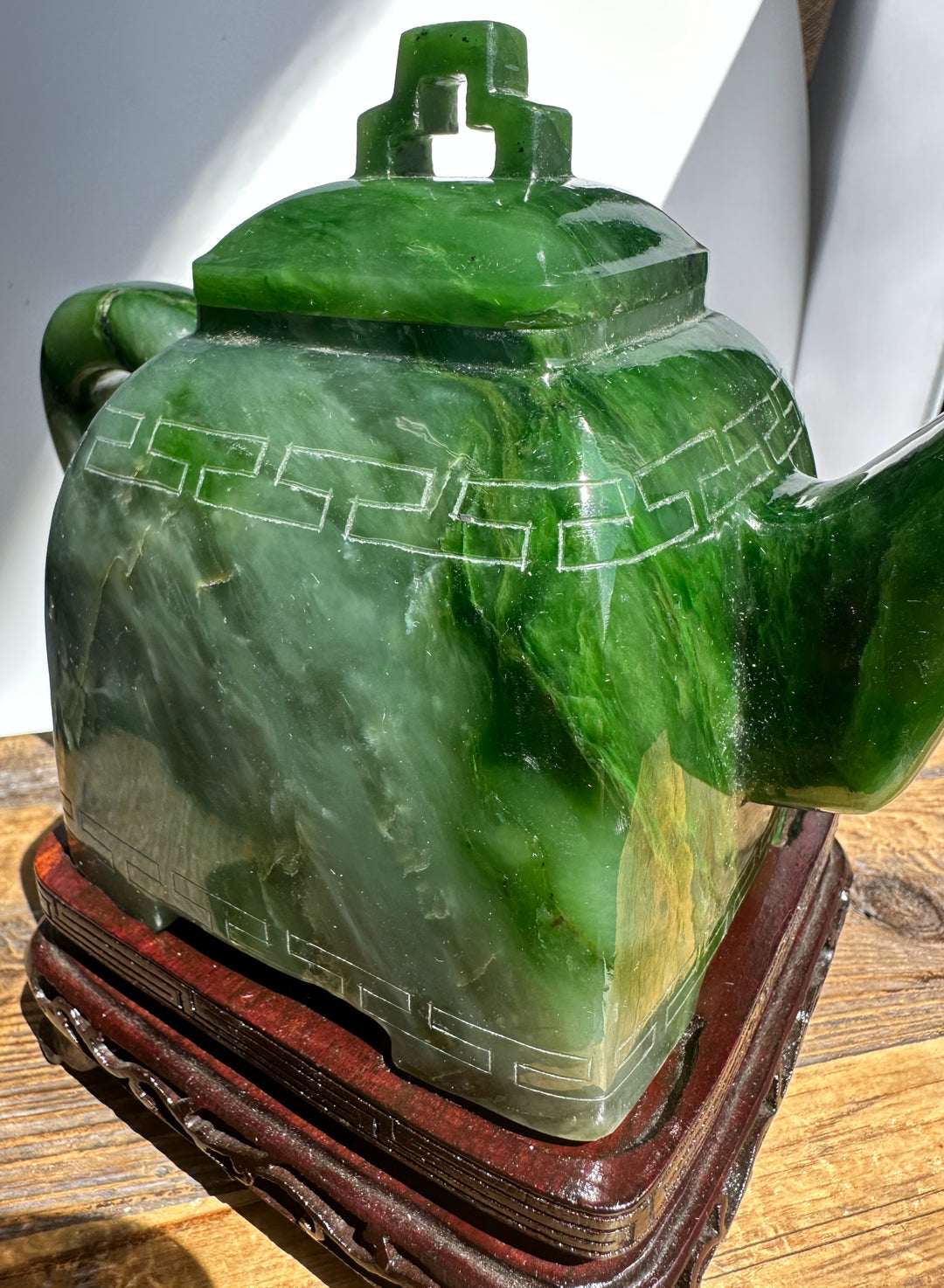 Close up of Polar Jade Teapot 7 inch with lid and curved handle on a carved wooden stand