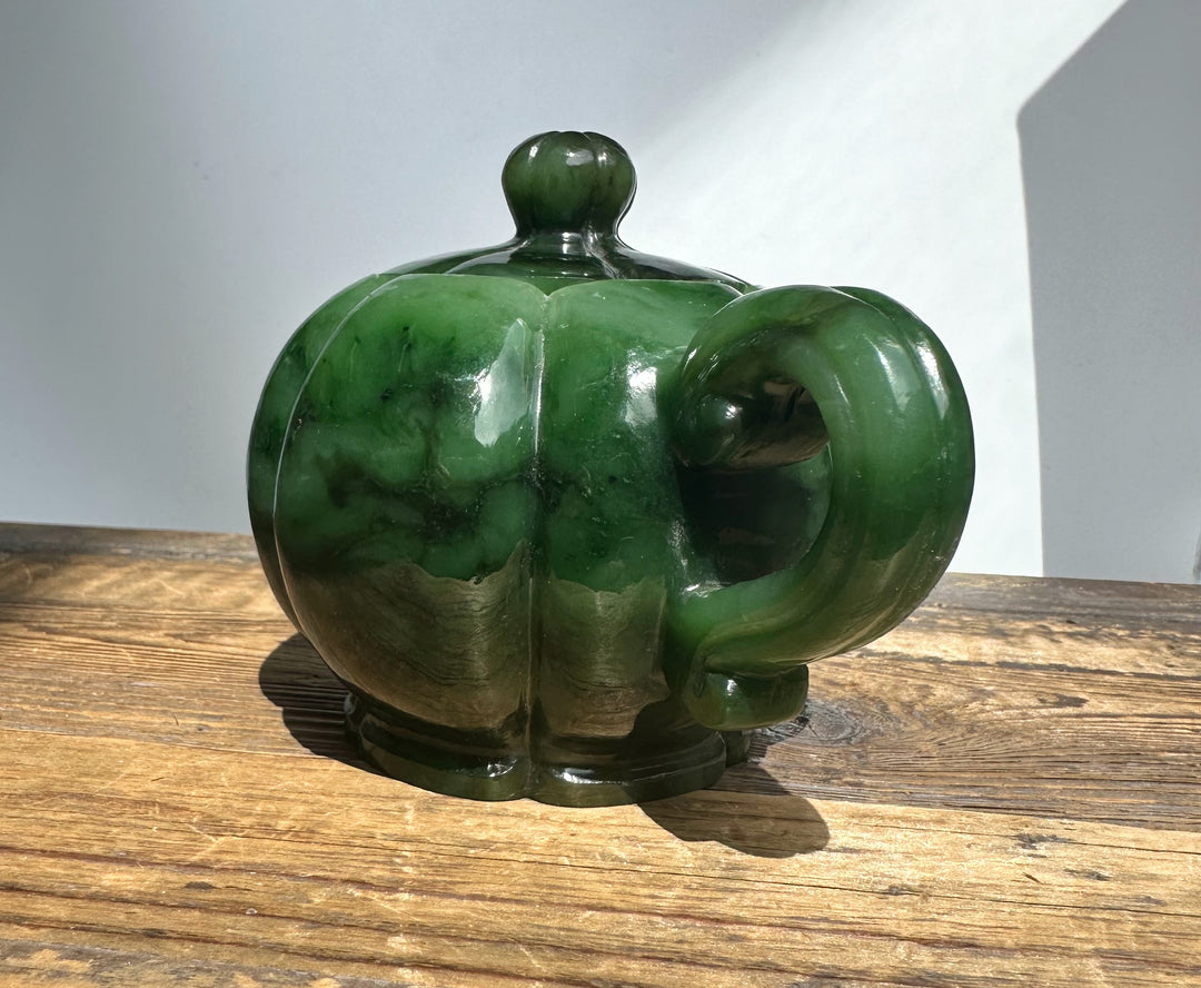 Polar Jade Teapot 6 inch from behind on a wood surface, green marbled glaze, round body, and curved handle.