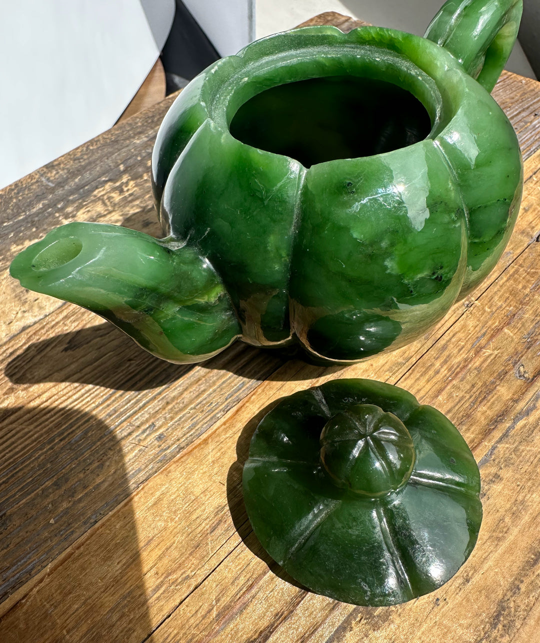 Green jade Polar Jade teapot with lid removed and resting beside on a wooden surface.