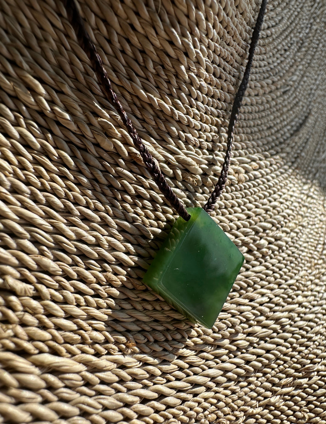 Green Jade pendant on a woven surface