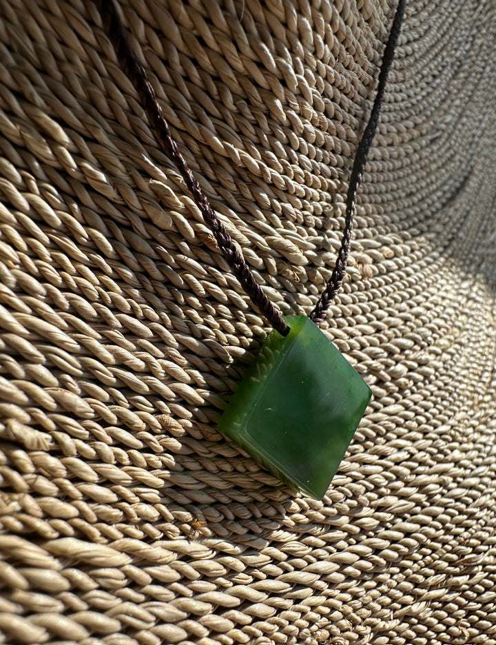 Green Jade pendant on a woven surface