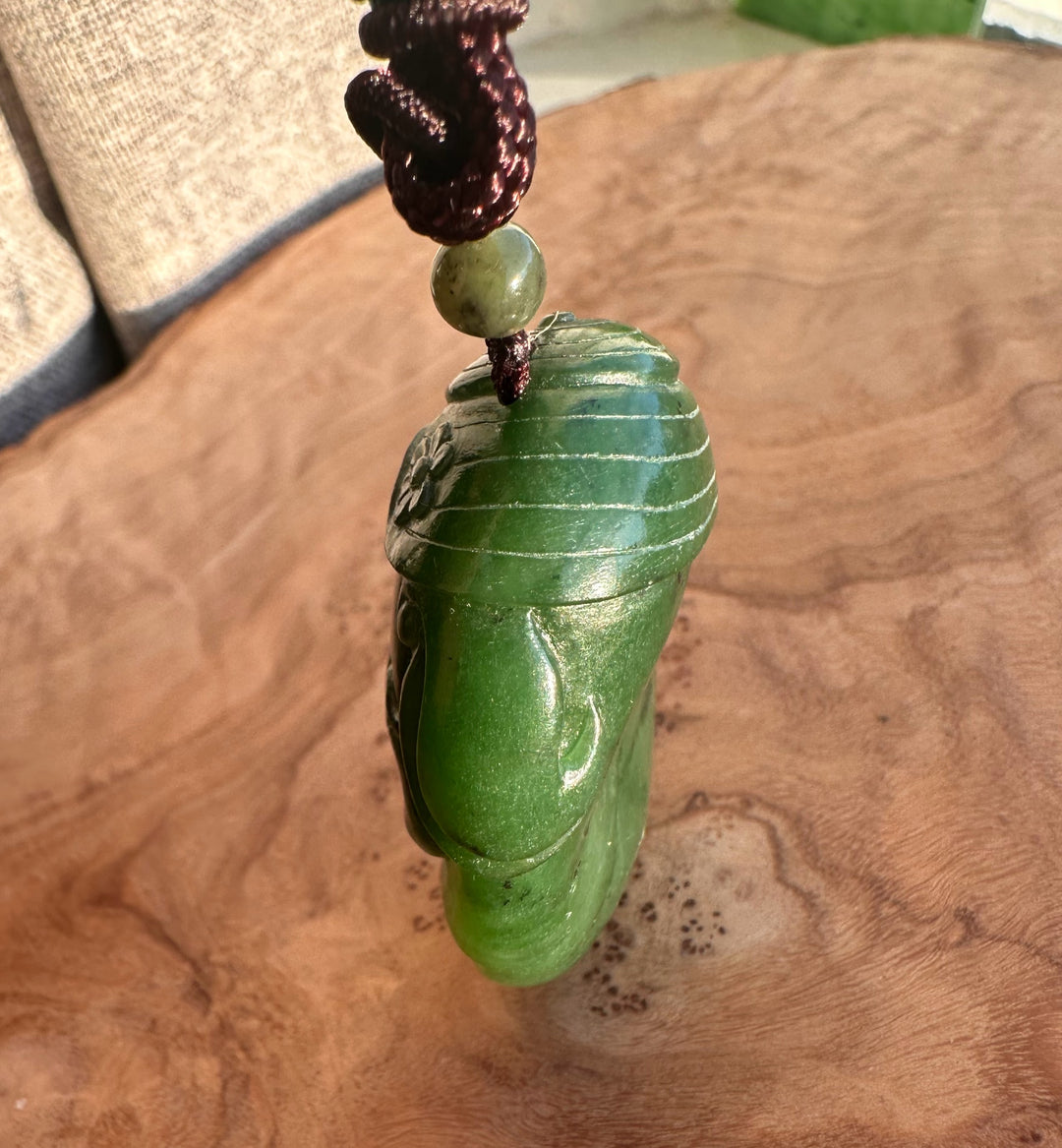 Hand carved Canadian jade pig pendant in rich green on a brown braided cord with a small bead