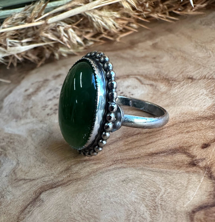 Vintage green jade ring featuring an oval cabochon encircled by a beaded silver bezel on a silver band