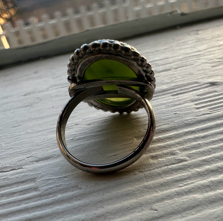 Vintage green jade ring in a silver and steel setting with a beaded edge viewed from the side.