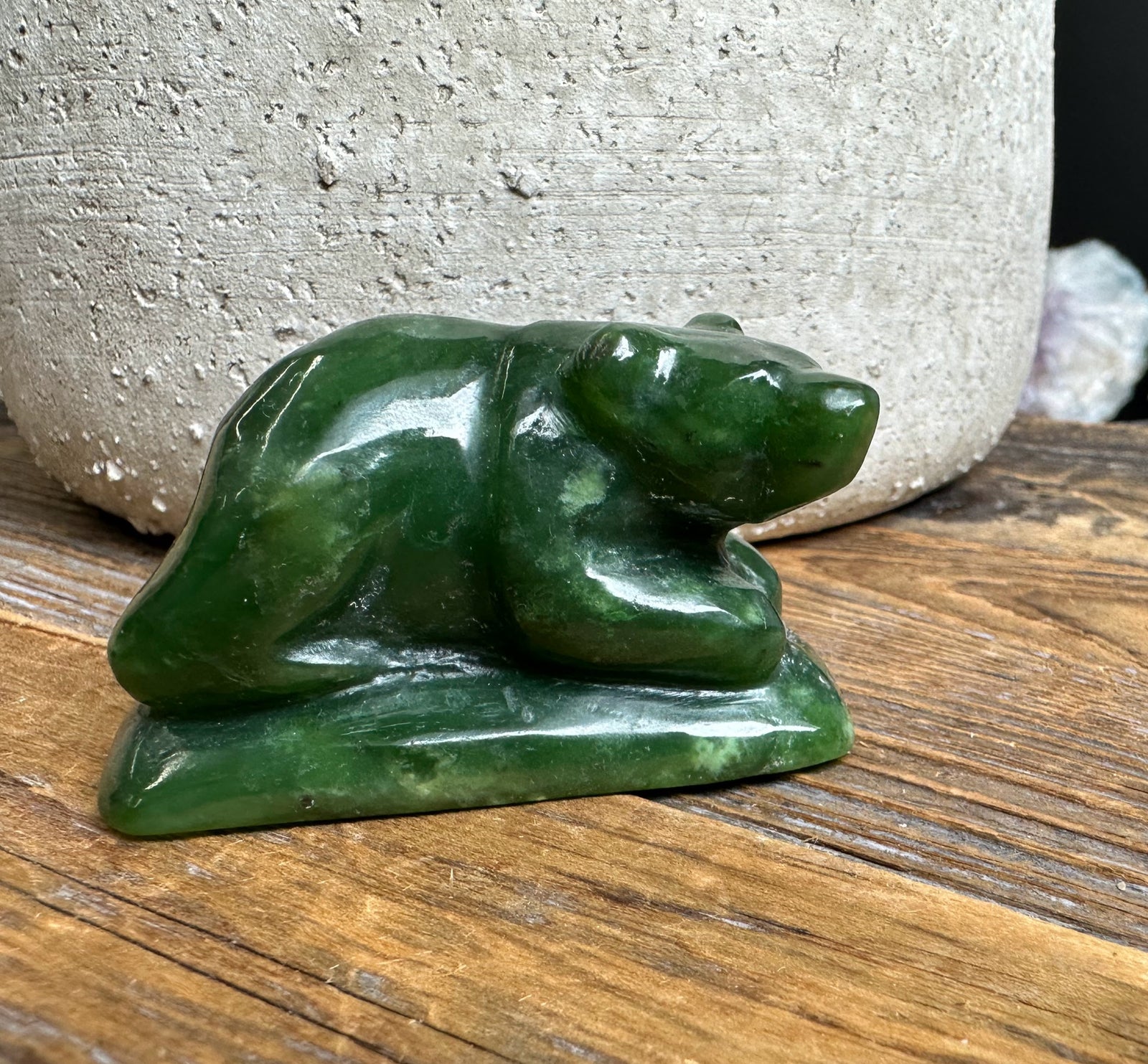 Dark green jade bear sculpture on a rectangular base resting on a wooden surface