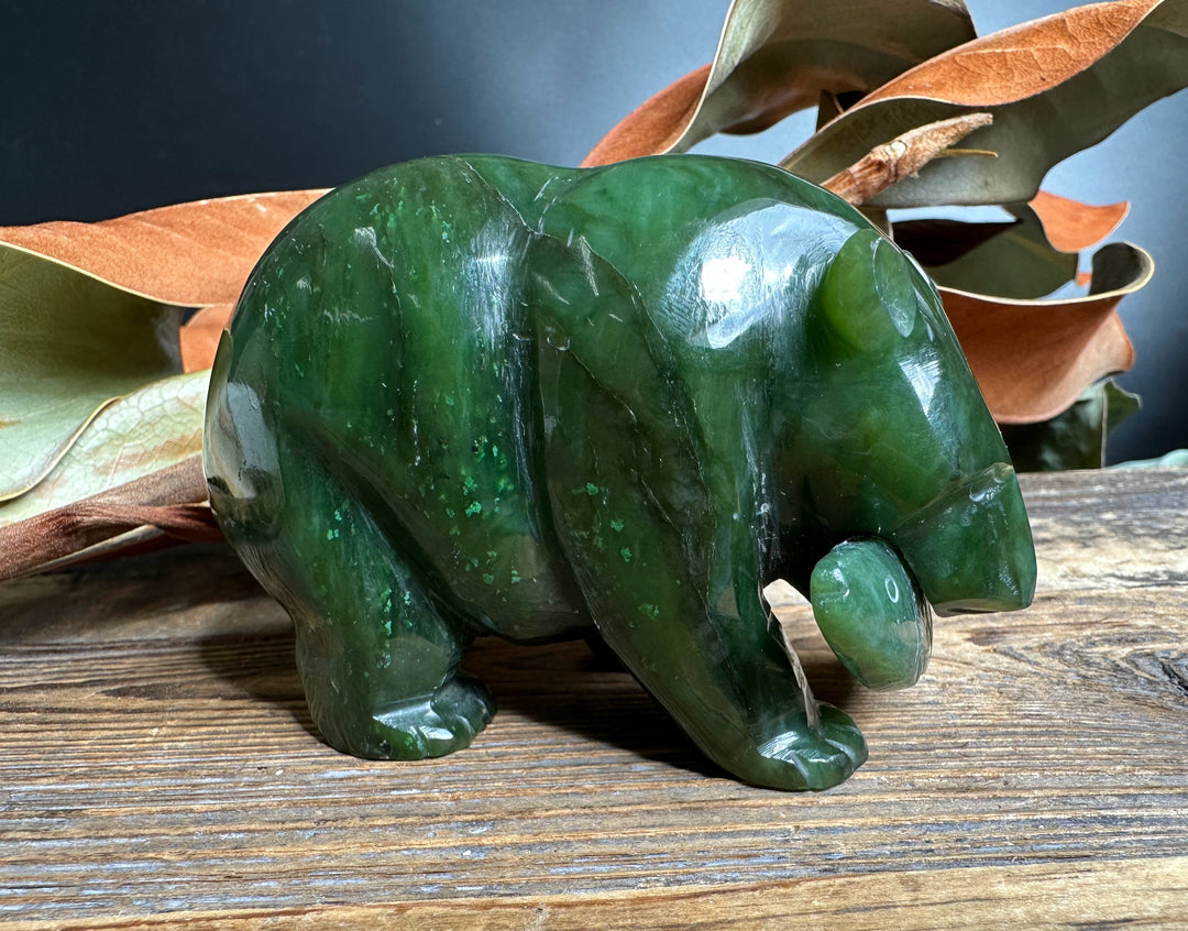 Glossy green jade bear figurine holding a carved jade fish in its mouth