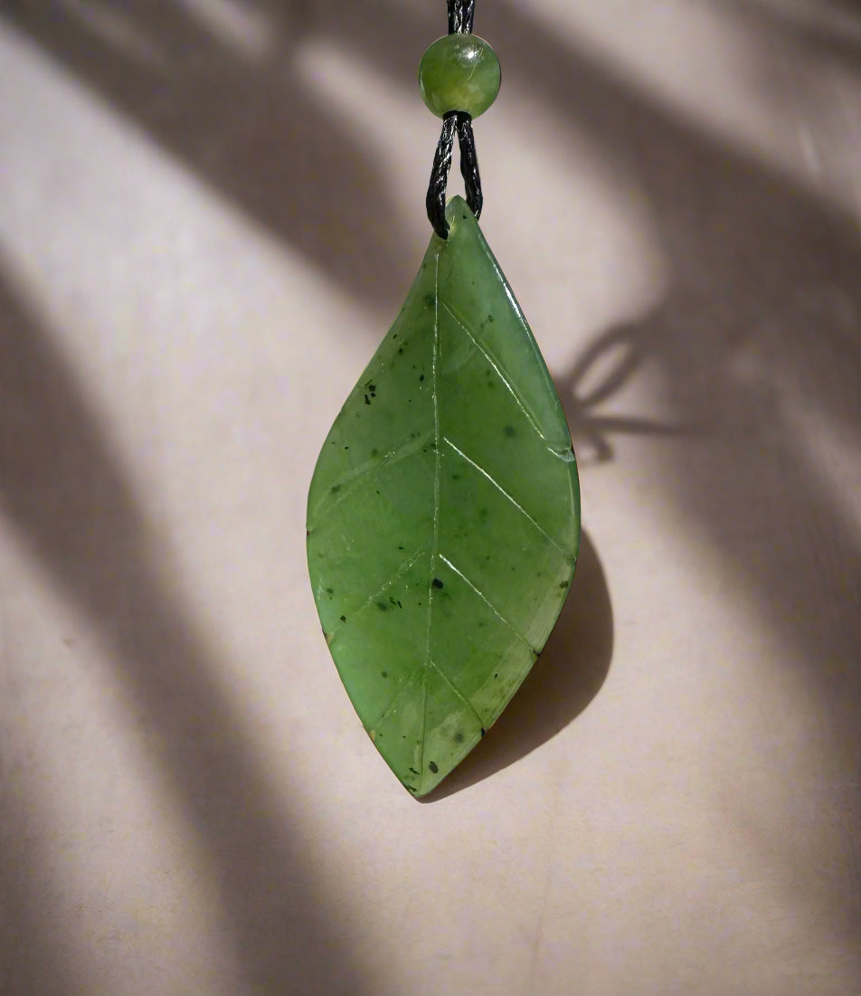 Canadian jade leaf pendant shaped like a leaf with carved veins, suspended on a black cord.
