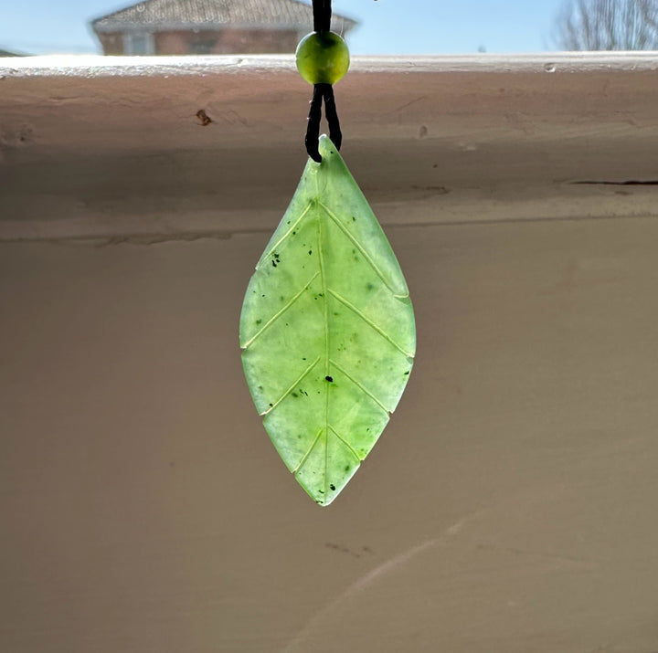 Canadian jade leaf pendant 38mm hanging from a black cord with a small green bead above