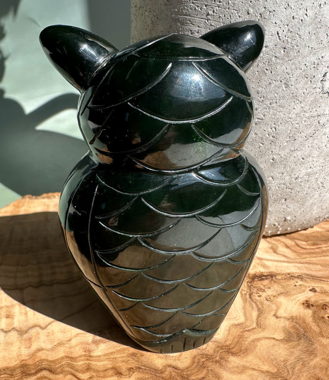 Back view of a dark green jade owl with feather scallop carving and a glossy finish