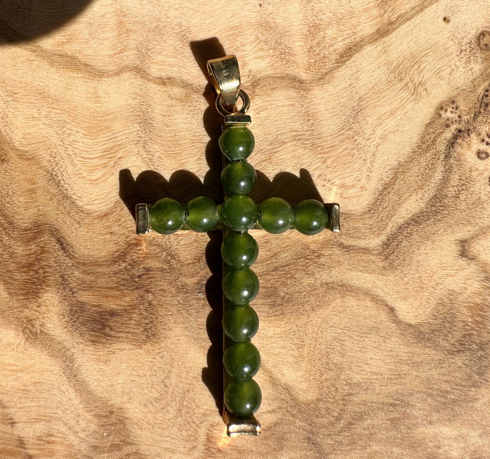 Vintage Jade Cross pendant with green round beads and metal fittings on wood background