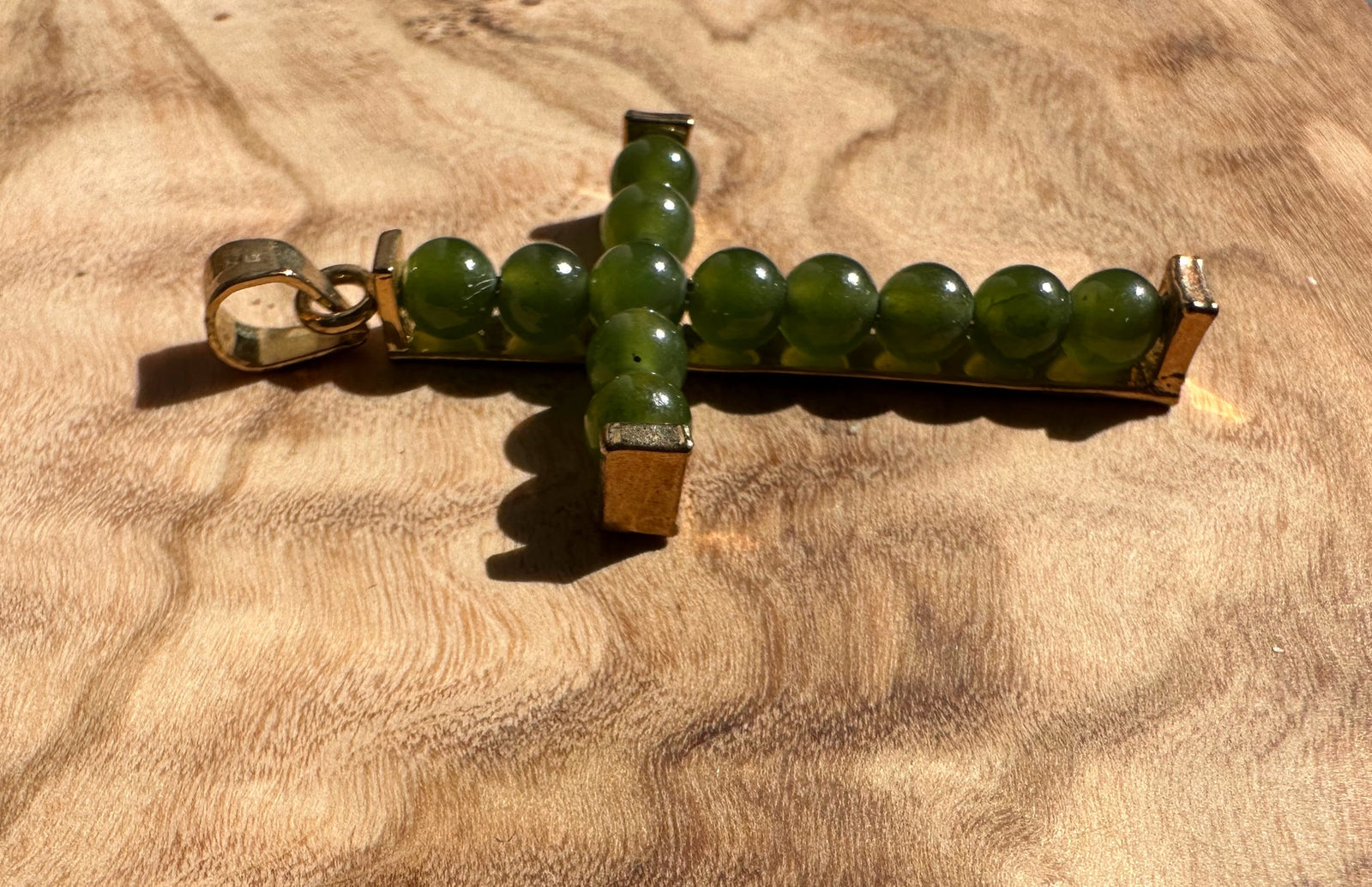 Vintage Jade Cross pendant oriented sideways showing a green bead cross with metal end caps