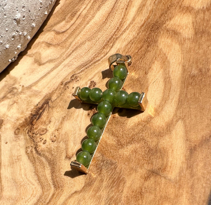 Vintage Jade Cross pendant arranged on a wood surface with green beads and a metal frame
