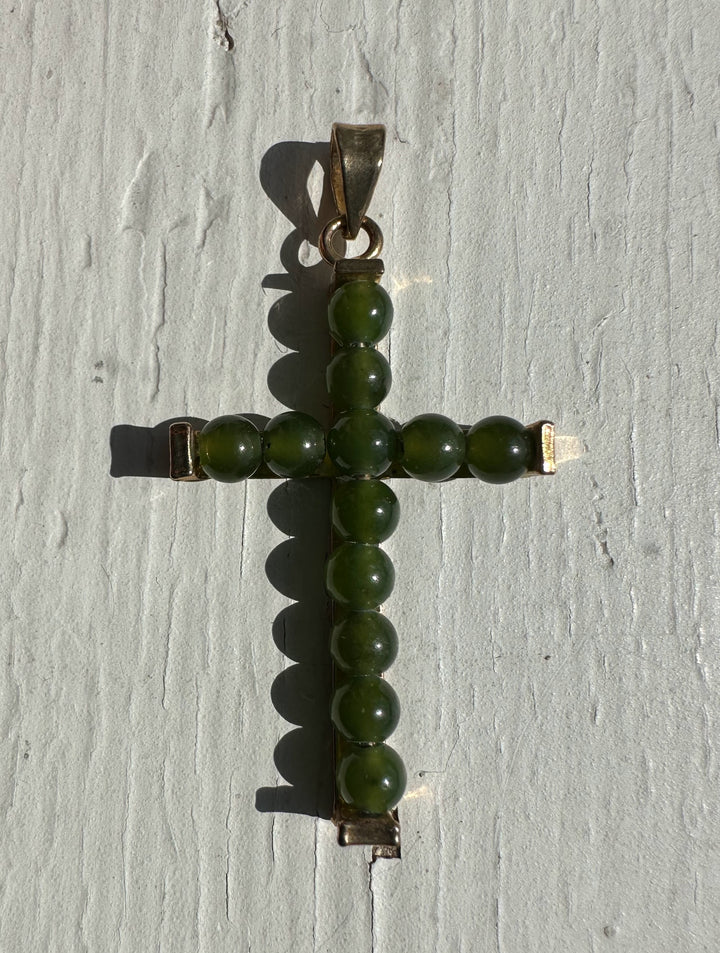 Vintage jade cross pendant formed by green beads set in metal with a bail at the top.