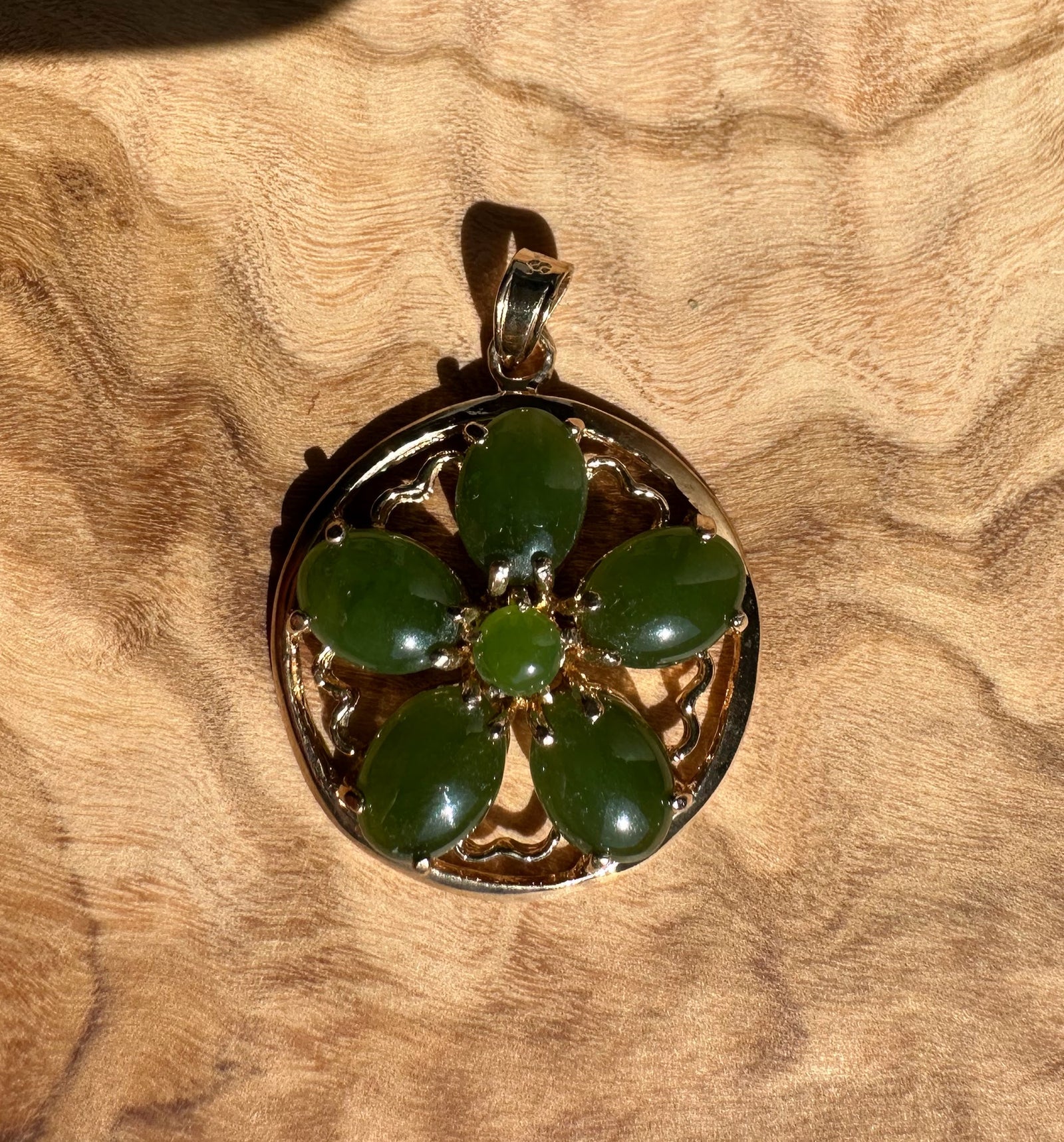 Vintage jade flower pendant featuring five oval green jade petals arranged around a central bead in a gold filigree setting