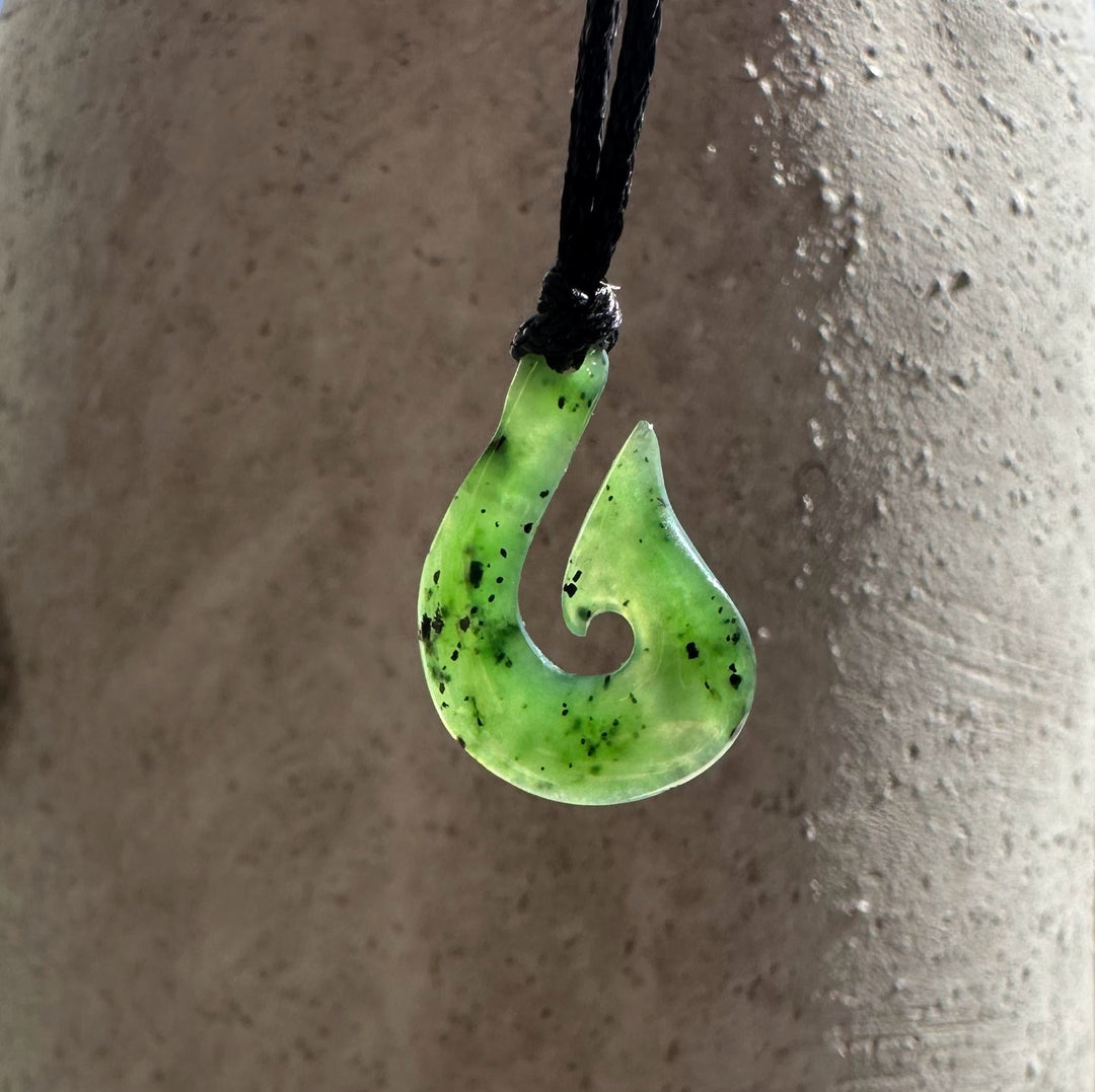 Green jade fishhook pendant with curved spiral cutout on a black cord