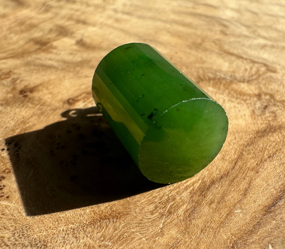Close-up of an 18mm green jade faceted pendant showing crisp facets against a beige background.