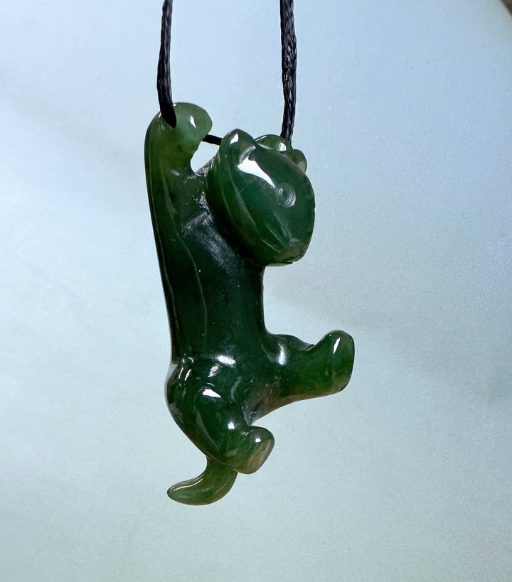 Side view of green jade cat pendant suspended on a cord