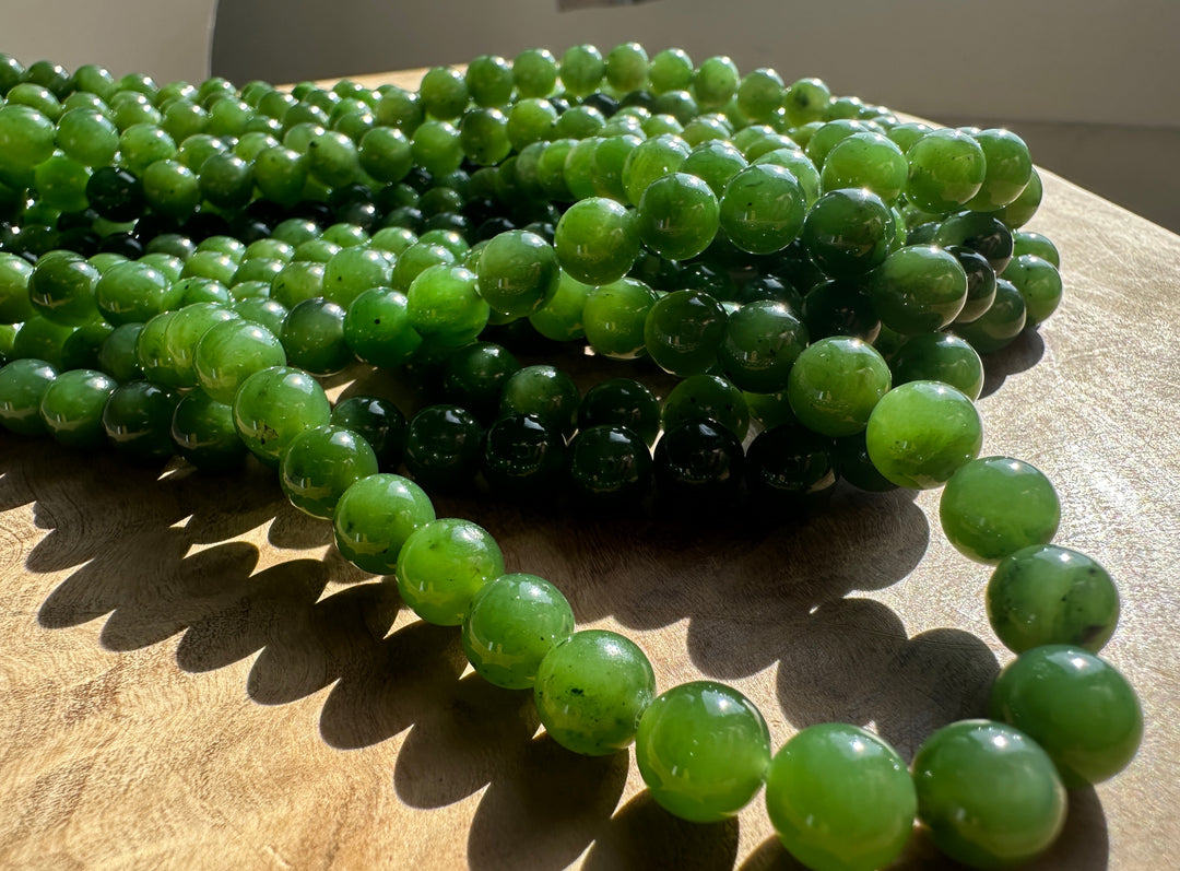 Green Canadian Nephrite Jade Unstrung Beads on a wooden base in sunlight