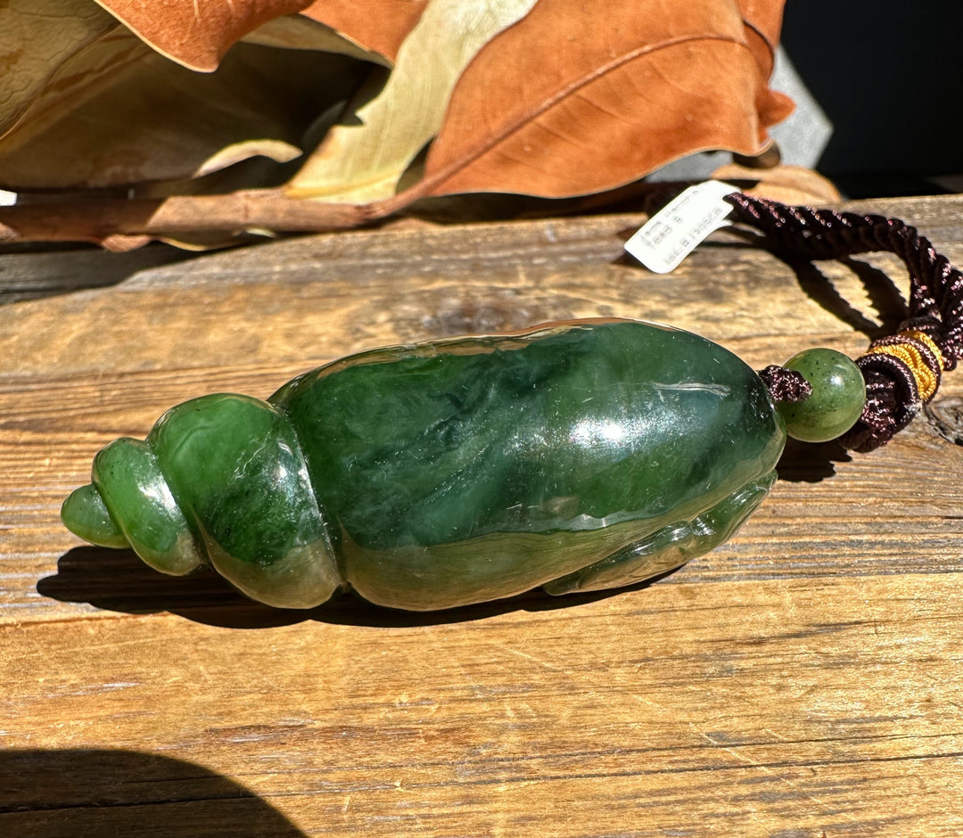 Close up of the green shell pendant with cord on a wooden surface