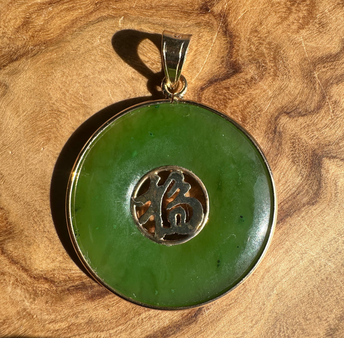 Vintage Canadian nephrite jade Fu Pi disc pendant with a gold bail on brown suede.