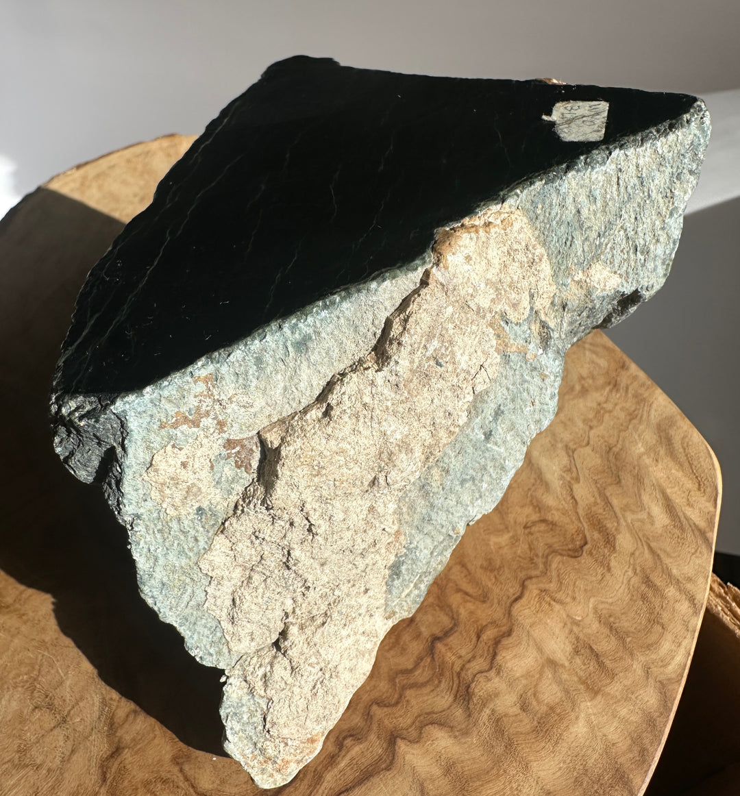 Dark Wyoming Black Jade slab with natural white veins and a small label sticker on the edge.